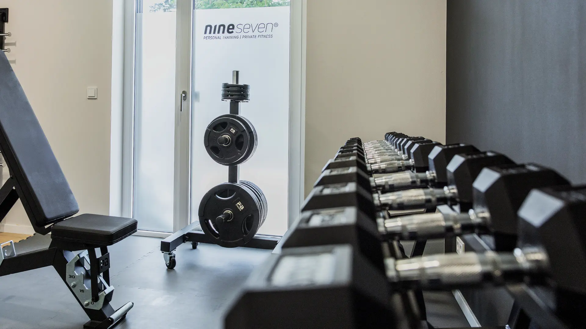 Das Bild zeigt das nineseven Fitnessstudio im Medical Center Windmühle in Unterpleichfeld. Die stilvolle und gut ausgestattete Trainingsfläche bietet eine Vielzahl an hochwertigen Fitnessgeräten für ein effektives Workout. Mit einem einladenden Ambiente und professioneller Ausstattung schafft das Studio eine motivierende Umgebung für Fitnessbegeisterte.